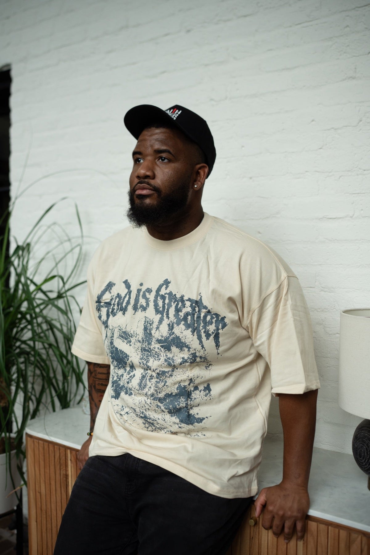 Model wearing God Is Greater Tee in cream